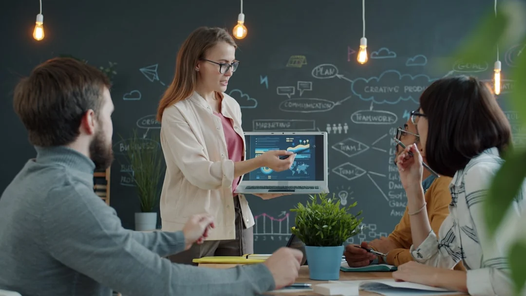Two colleagues collaborate on a marketing strategy using a whiteboard, focusing on user-generated content.